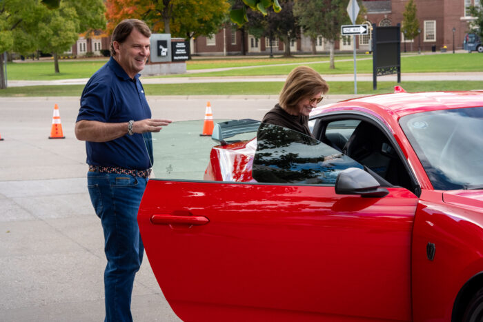 Monica Langley and Jim Farley next to a red Ford car