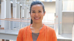 Portrait image of Sara Hsu, clinical associate professor of supply chain management, dressed in an orange sweater and grey blouse, standing in the business building atrium.