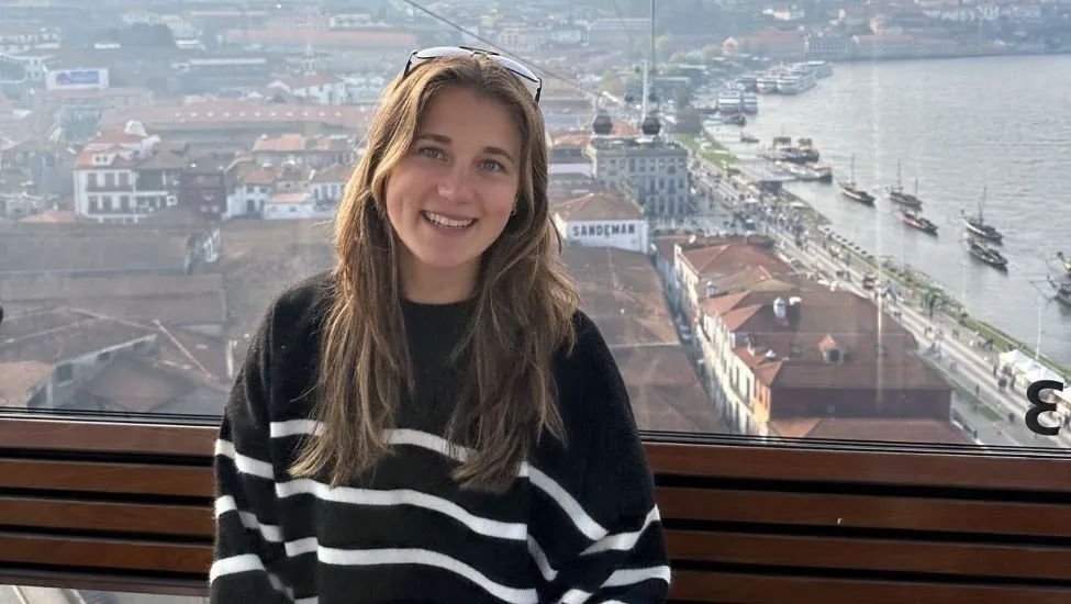 Amy Poffenberger, with brownish-blonde hair falling past her shoulders and wearing a black sweater with white stripes and sunglasses perched atop her head poses above the Mediterranean coastline in Malaga, near the south of Spain.