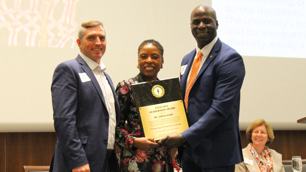 Jefferson Johnson (left) and Clarence Vaughn (right), present the inaugural Haslam Inclusive Leadership Award to Amelia Hart (middle), all dressed in business attire.
