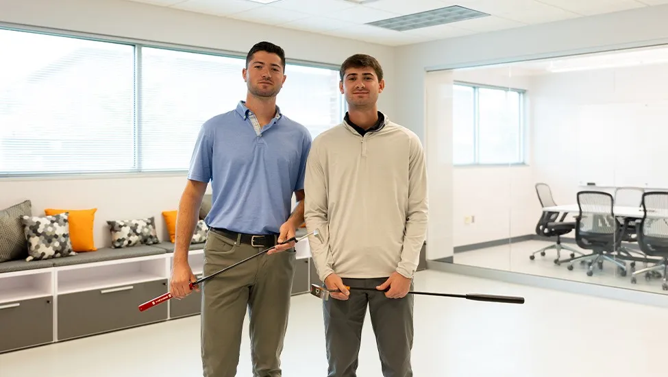Tony Tuber and Mike Tuber pose in a conference room with their T Squared putters