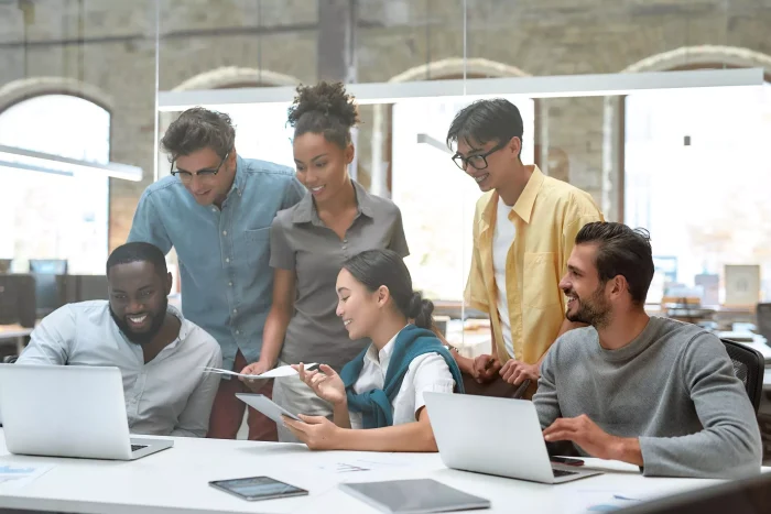 A team of multi-ethnic young professionals in casual garb taking an MSBA program together find success working on problem for class.