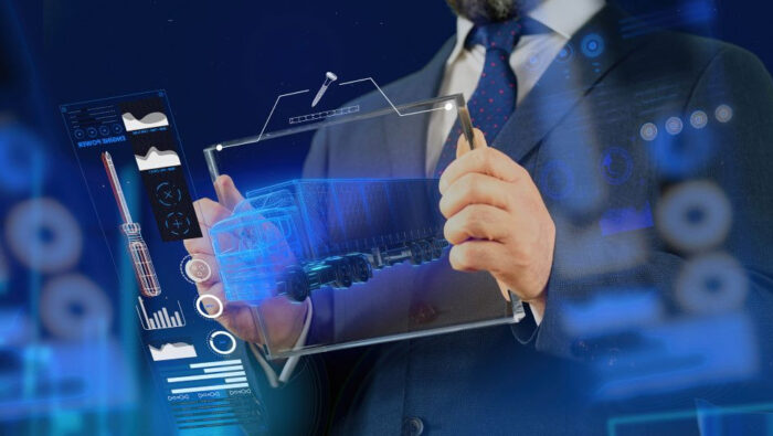 Man in a business suit wearing blue tie with tiny red dots, seen only from his bearded chin down to mid torso, holding a transparent device with a translucent image of a freight truck in its middle with various computational symbols on its right side.