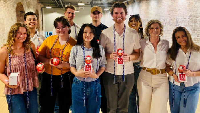 The multicultural members of Haslam's first International Business cohort dressed in casual clothing pose with Sara Easler (second from right) holding graduation gifts.