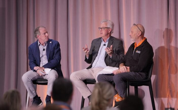 Tom Goldsby, Kevin Sweeney and Ted Stank holding a discussion on a dais before an audience.