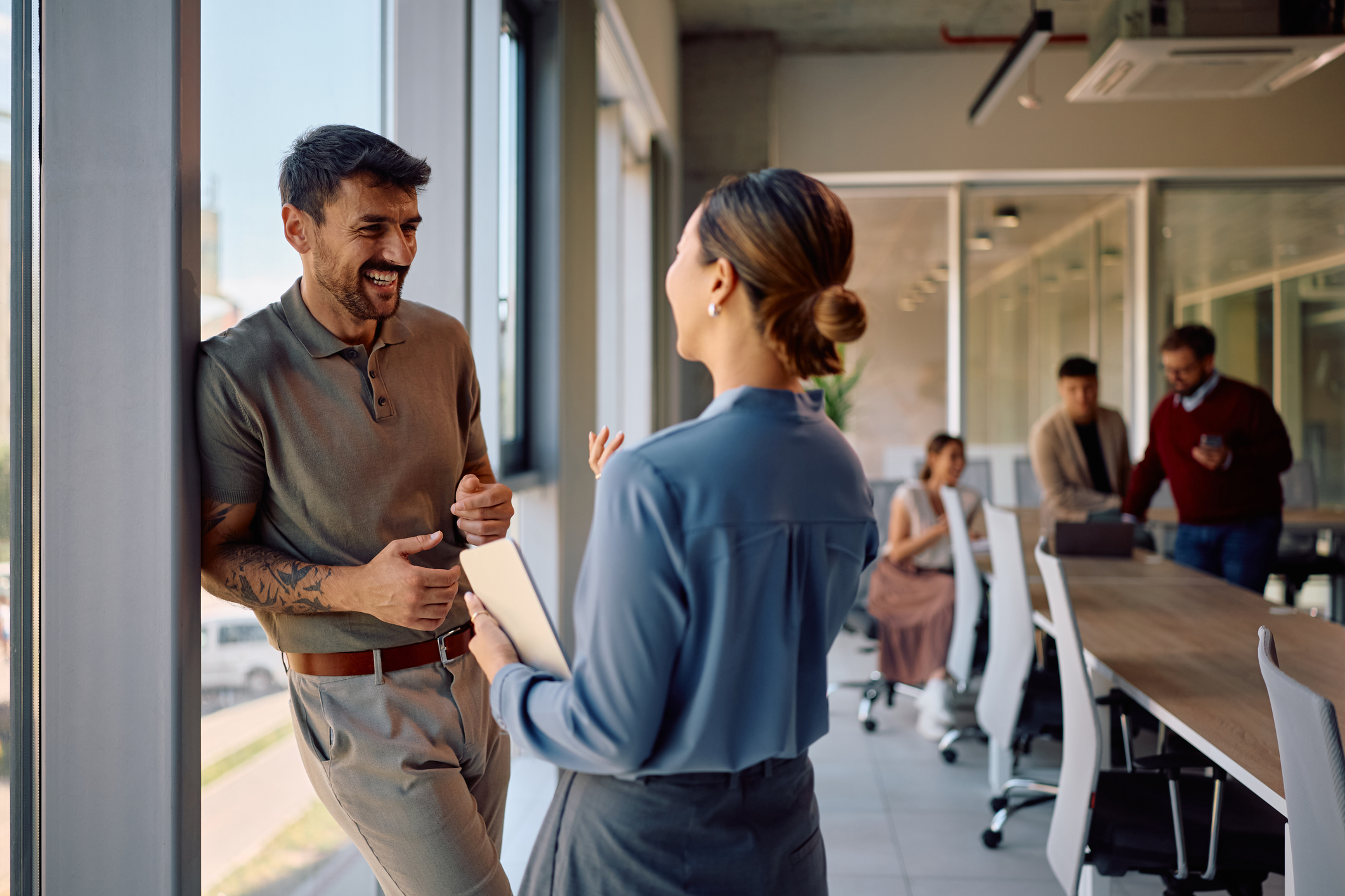 Happy business man communicating with female colleague while working in the office.