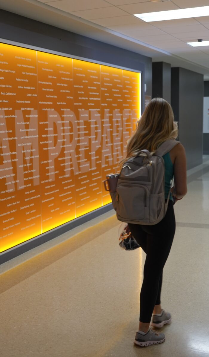 Student walking in hallway next to Haslam Prepared wall