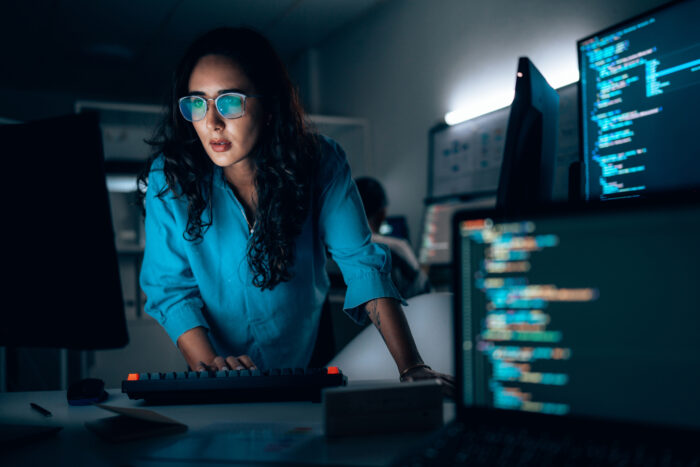 Female software developer coding at night in office